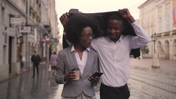 Afro Man and Woman Hiding From Rain Under Jacket