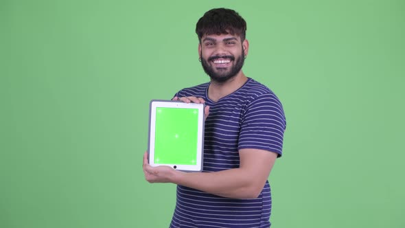 Happy Young Overweight Bearded Indian Man Showing Digital Tablet