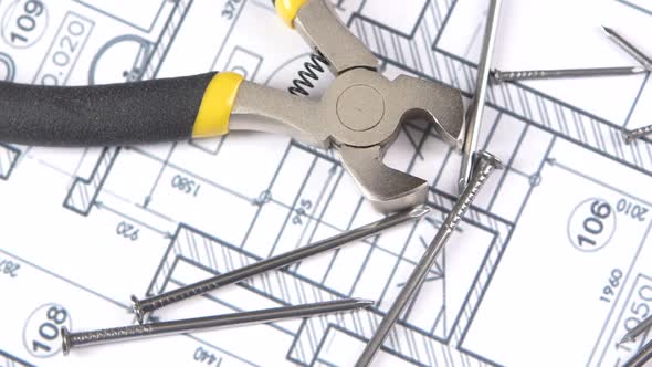 Wire Cutters with Yellow, Gray Handle on Building Plan, Scheme Among Nails, Rotation, Close Up