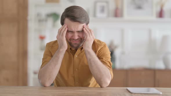 Young Man having Headache while Sitting in Office