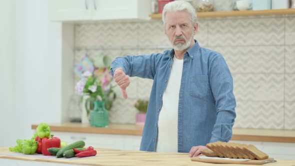 Old Man Showing Thumbs Down While Standing in Kitchen