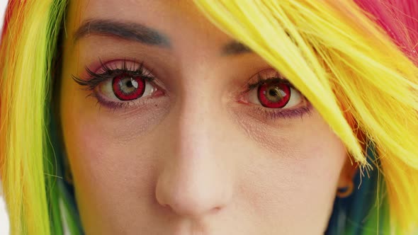 Rainbowhaired Girl with Red Eyes and Long Dark Lashes Slowly Looking Into the Camera Extreme Closeup