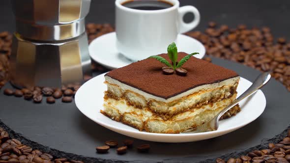 Portion of Traditional Italian Tiramisu dessert, cup of espresso, mocha and coffee beans