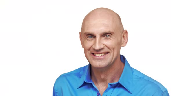 Bold Middleaged Caucasian Male in Blue Shirt Standing on White Background Smiling and Waving Head