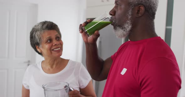 Senior african american man and woman drinking fruit and vegetable health drinks at home