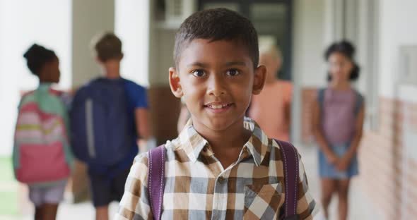 Video of happy biracial boy standing at school corridor