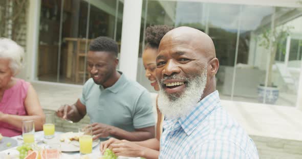 Portrait of happy african american family talking and having breakfast in garden