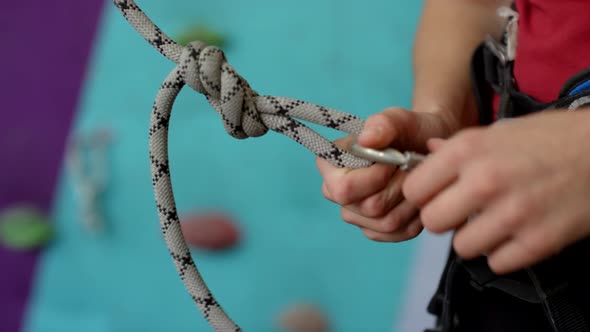 Female Climber Clasping Carabiner onto Harness at Climbing Gym
