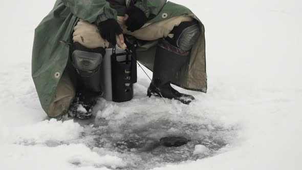 Man is catching fish on frozen lake