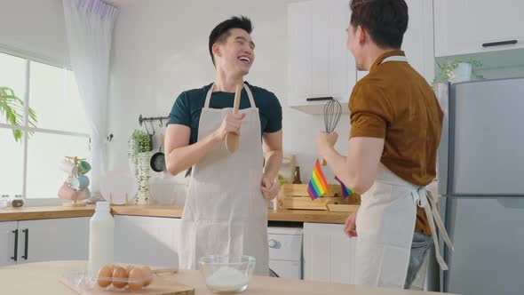 Asian happy handsome man gay couple funny sing and dance together in kitchen at home.