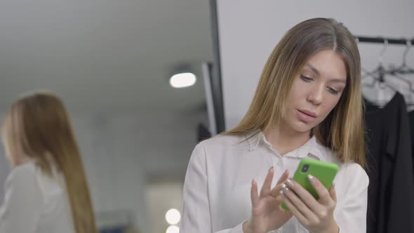 Young Woman on the Right Messaging Online Scrolling Smartphone Screen Thinking Reflecting in Mirror