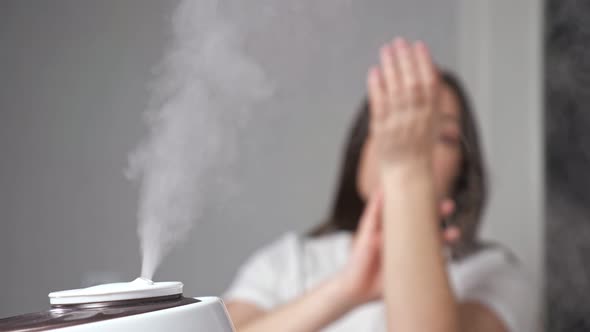 Young Woman Applies Cream on Arms Enjoying Moisturized Air