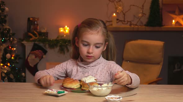 Little Girl Is Spreading Cream on the Delicious Cinnamon Rolls
