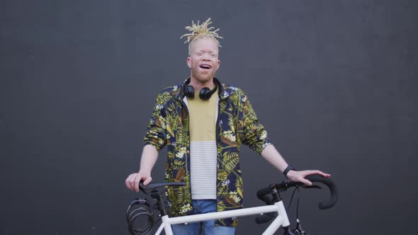 Portrait of smiling albino african american man with dreadlocks looking at camera with bike