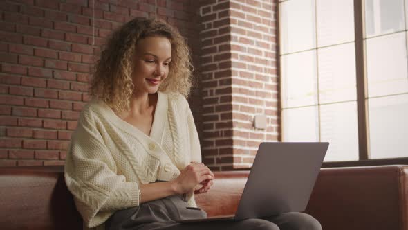 Low Angle Shot of a Caucasian Curly Blond Woman on a Video Call on Her Laptop Computer