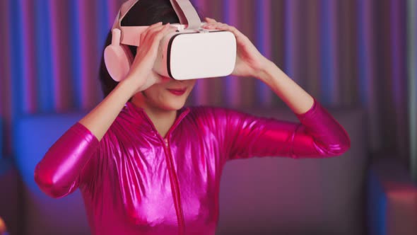 Young asian woman is using virtual reality headset. Neon light studio portrait