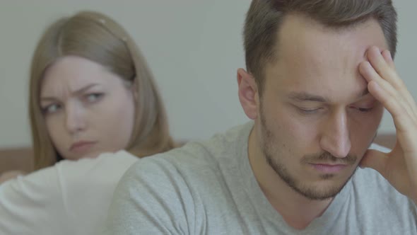 Close-up Portrait of Sad Man and Woman Sitting Back To Back with Unhappy Faces at Home