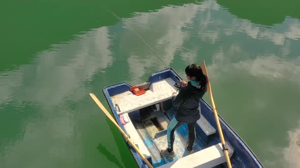 Woman on the Boat Catches a Fish on Spinning in Norway