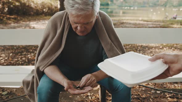 Poor Elderly Homeless Man Counting Left Coins in the Park and Receiving Charity Meal 