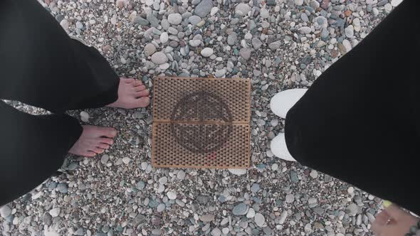 Two Women Doing a Step to the Sadhu Board on the Seashore and Holding Hands