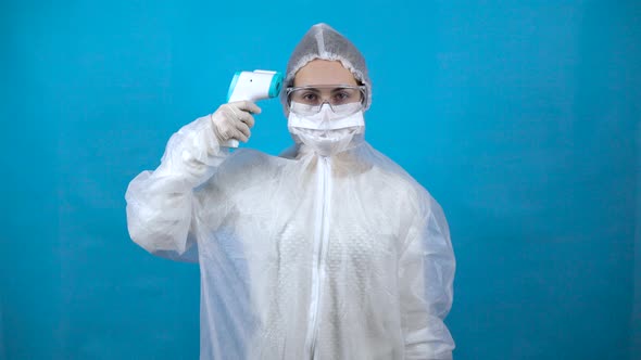 Young Woman in a Protective Suit with an Infrared Thermometer. The Girl Measures the Temperature