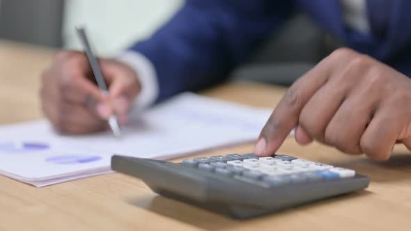 Close Up of African Businessman Using Calculator at Work