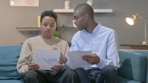 Couple Reading Documents Together on Sofa