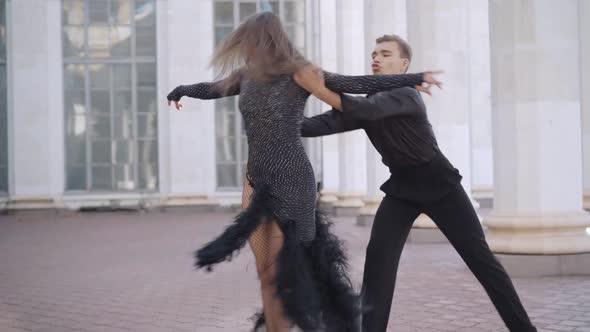 Handsome Young Man Dancing Paso Doble with Partner in Sunny City at Urban Building with Columns