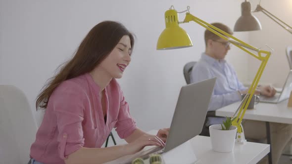 Asian Woman Operator with Headset Sittig in Front of Laptop Friendly Speaking with a Client