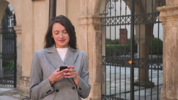 Pretty Smiling Woman Typing on Phone in the Street