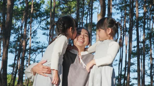 Two cute siblings girls having fun with a beautiful young mother in the park.