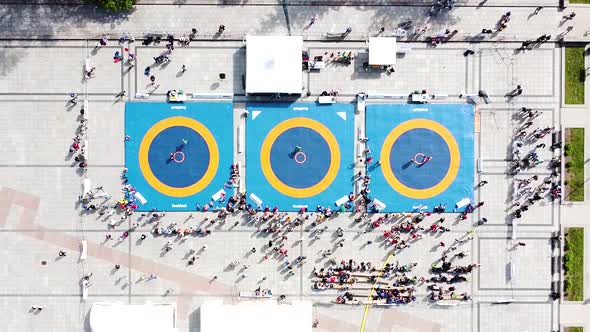 Martial arts competition outdoors on sunny day, aerial top down ascend view