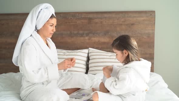 Cute Mother and Daughter in Dressing Gowns Use Face Masks and Patches at Home, Quarantine 