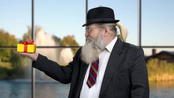 Bearded Businessman Pointing at Gift Box.