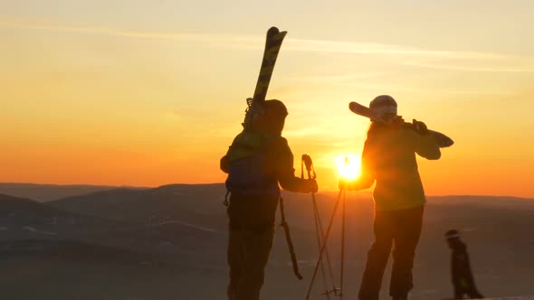 A Couple of Mountain Skiers in Love Stands on the Slope of the Mountain and Admires the Sunset