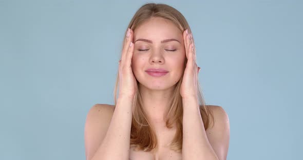 Adorable Young Woman Portrait in Studio. Doing Massage of Her Temples with Enjoyment