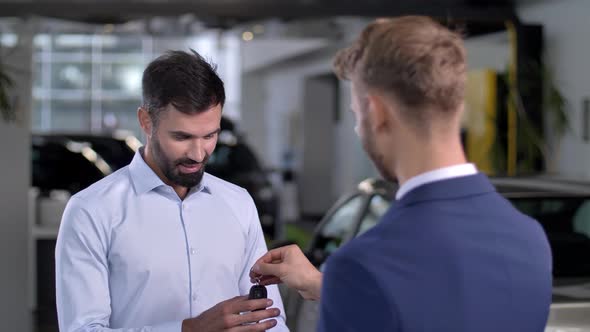 Joyful Man Getting Keys To Car at Auto Dealership