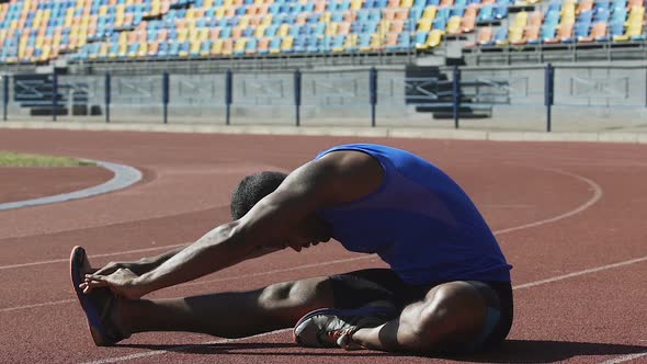 Hispanic Athlete Warming His Back Doing Flexibility Exercises on Race Track