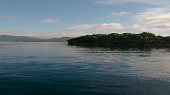 View from a boat on the driving towards and getting close to a lone island. Marlborough Sounds. Near