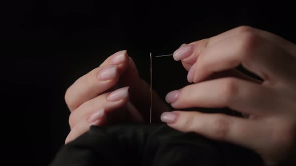 Slow motion shot of thread passing through sewing needle. woman sewing project by hand