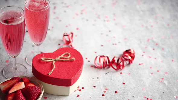 Bottle of Rose Champagne, Glasses with Fresh Strawberries and Heart Shaped Gift