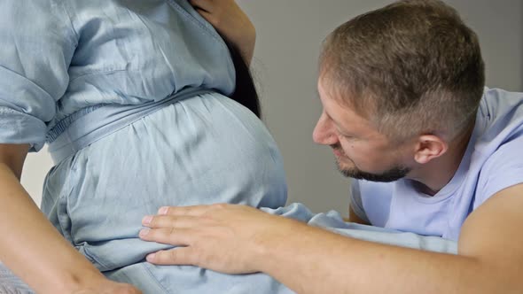 Happy Man Stroking and Kissing the Belly of His Pregnant Wife. Waiting for the Birth of a Child.