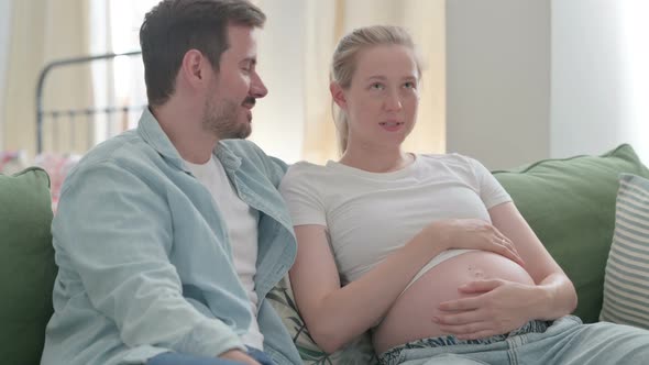 Talking Pregnant Couple Relaxing at Home Discussing Future