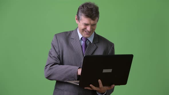 Mature Handsome Businessman Against Green Background