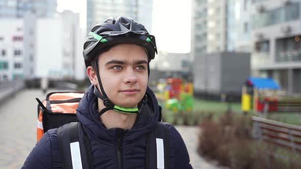 Young Delivery Man in Helmet Walking Down Street