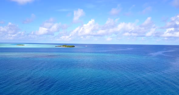 Beautiful flying tourism shot of a white sand paradise beach and blue sea background in colourful 4K