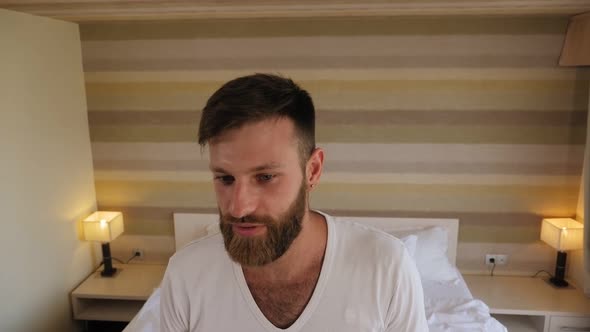 A Tired Bearded Man Enters the Hotel Rooms and Falls on the Bed