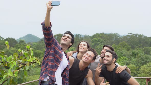 Happy group of friends taking a photo in the mountain with backpack to travel adventure.