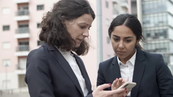 Concentrated Businesswomen Using Smartphone on Street