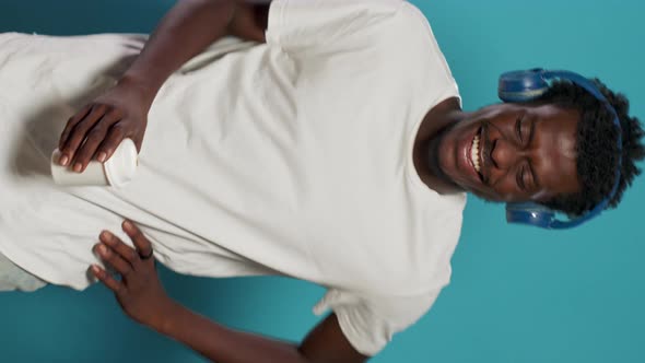 Portrait of Man with Headphones Jumping and Dancing to Song